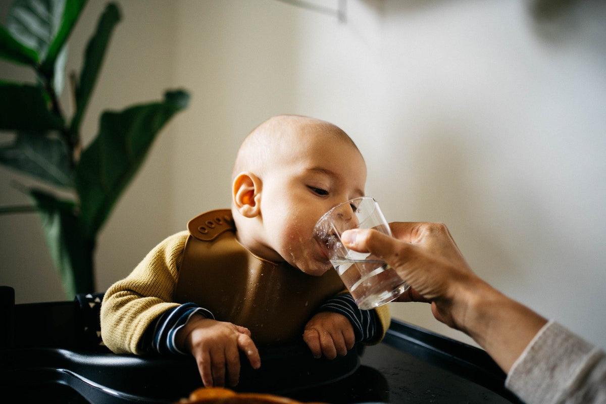 Baby trinkt aus dem offenen Becher