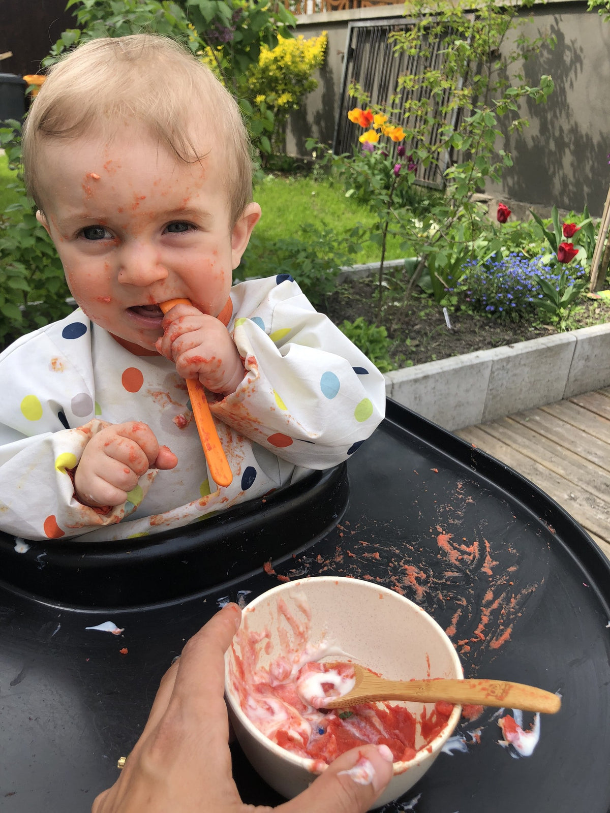 Baby isst eine Karotte im Hochstuhl